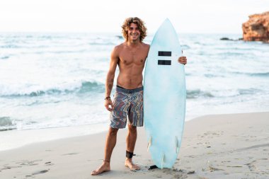 Kafkasyalı genç adam gün doğumunda sörf yapmak için erken kalkar.