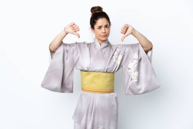 Kimono giyen bir kadın izole edilmiş arka planda baş parmağını iki eliyle gösteriyor.