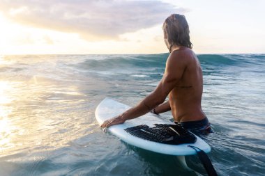 Kafkasyalı genç adam gün doğumunda sörf yapmak için erken kalkar.