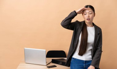 İş yerindeki Çinli iş kadını yan tarafa bakarken sürpriz jest yapıyor.