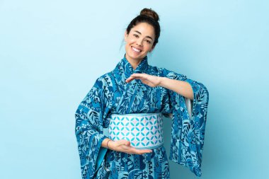 Kimono giyen bir kadın, izole edilmiş arka planda bir ilan vermek için sanal bir mekan tutuyor.