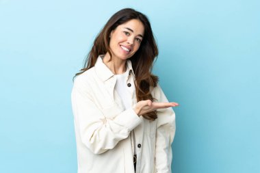 Woman over isolated background presenting an idea while looking smiling towards