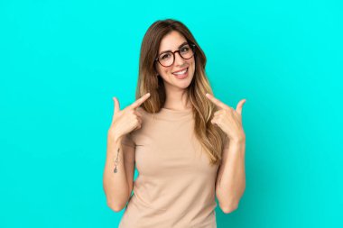 Mavi arka planda izole edilmiş beyaz bir kadın baş parmak işareti yapıyor.