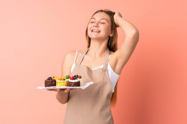 Ukraynalı aşçı pembe arka planda izole edilmiş bir kek tutuyor.