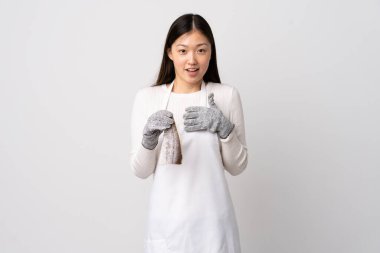 Çinli balıkçı önlük takıyor ve kendini gösteren beyaz bir arka plan üzerinde çiğ balık tutuyor.