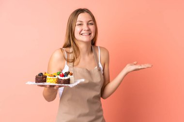 Pastacı Ukraynalı şef pembe arka planda izole edilmiş bir kek tutuyor.