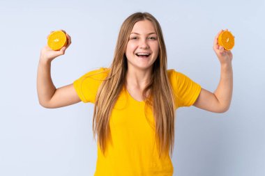 Genç Ukraynalı bir kız mavi arka planda portakal tutuyor.