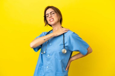 Doktor kadın, sarı arka planda izole edilmiş omuz ağrısı çektiği için çabaladığı için.