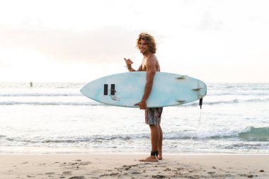 Kafkasyalı genç adam gün doğumunda sörf yapmak için erken kalkar.