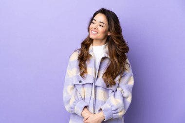 İzole edilmiş mor arka planda bir kadın yana bakıyor ve gülümsüyor.