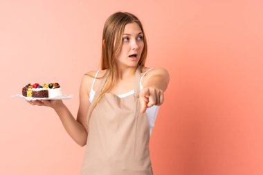 Ukraynalı aşçı pembe arka planda izole edilmiş bir kek tutuyor.