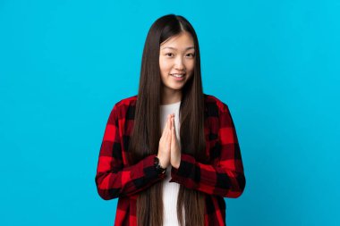 İzole edilmiş mavi geçmişi olan genç bir Çinli kız avuç içlerini bir arada tutuyor. İnsan bir şey ister.