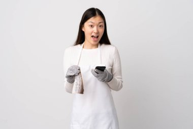 Çinli balıkçı önlük takıyor ve beyaz arka planda çiğ balık tutuyor.