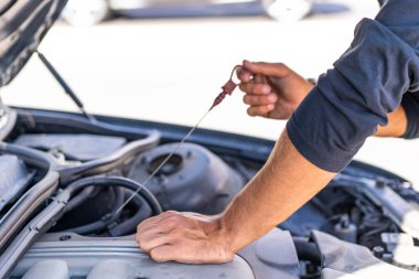 Genç beyaz bir adam arabasındaki arızayı düzeltmeye çalışıyor.