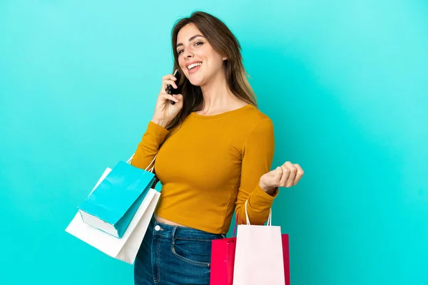 Caucasian Woman Isolated Blue Background Holding Shopping Bags Calling Friend — ストック写真