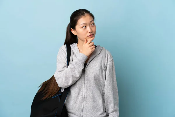 年轻的中国女子 身披运动包 背景深蓝色 令人怀疑 — 图库照片