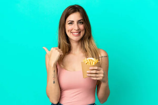 Caucasian Woman Holding Fried Chips Isolated Blue Background Pointing Side — ストック写真