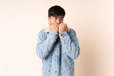 Tecrit edilmiş bej arka planda yakışıklı bir adam gergin ve korkmuş, elleriyle suni teneffüs yapıyor.