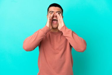 Soyutlanmış mavi arka planda genç yakışıklı bir adam bağırıyor ve bir şeyler söylüyor.