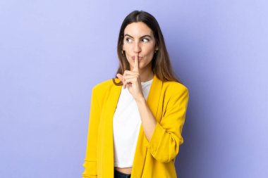 İzole edilmiş arka planda genç beyaz bir kadın sessizce hareket ettiğini gösteriyor. Parmağını ağzına sokuyor.