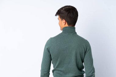 Yakışıklı adam arka tarafta mavi arka planda ve yana bakıyor.