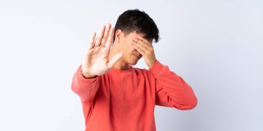 Yakışıklı bir adam mavi arka planda, jesti durduruyor ve yüzünü kapatıyor.