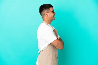 Restoran garsonu mavi arka planda, yan pozisyonda.