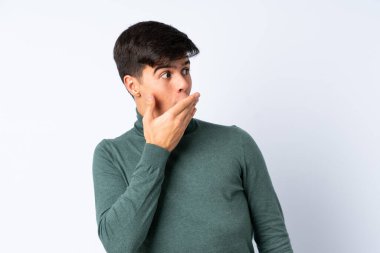 Yakışıklı adam mavi arka planda, yana bakarken sürpriz jest yapıyor.