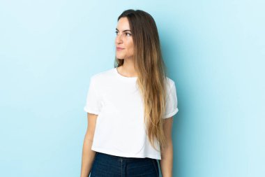 Kafkasyalı genç bir kadın soyutlanmış bir arka planda yan tarafa bakıyor.