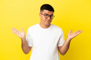 Soyutlanmış sarı arka planda genç yakışıklı bir adam şüpheli hareketler yapıyor.