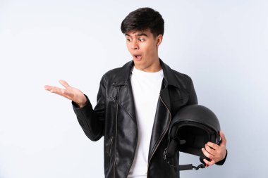 İzole edilmiş mavi arka plan üzerinde motosiklet kaskı olan bir adam...