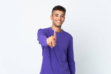 Beyaz arka planda izole edilmiş genç Brezilyalı adam parmağını kaldırıyor ve gösteriyor.