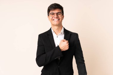 İzole edilmiş bej arka planda bir iş adamı zaferi kutluyor.