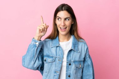 Pembe arka planda izole edilmiş genç beyaz kadın çözümü bulmak için parmağını kaldırıyor.
