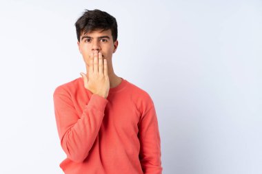 İzole edilmiş mavi arka planda yakışıklı bir adam. Ağzını eliyle kapatıyor.
