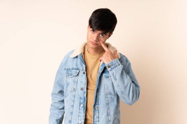 İzole edilmiş bej arka planda yakışıklı bir adam bir şey gösteriyor.