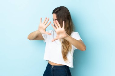 İzole edilmiş arka planda genç beyaz kadın ellerini öne uzatıyor.