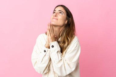 Pembe arka planda izole edilmiş genç beyaz kadın avuç içlerini bir arada tutuyor. İnsan bir şey ister.