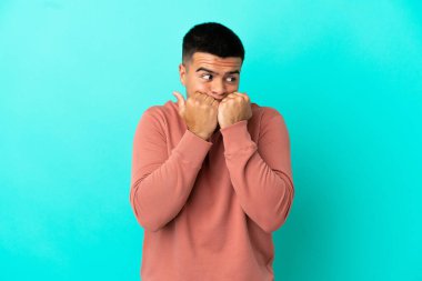 Genç, yakışıklı, soyutlanmış, mavi arka planda gergin ve korkmuş bir adam elleriyle suni teneffüs yapıyor.
