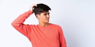 Mavi arka planda yakışıklı bir adam. Kafasını kaşırken şüpheleri var.