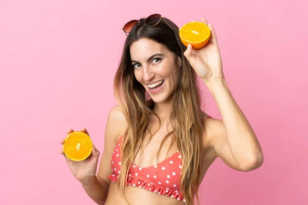 若いですブロンド女性上の隔離されたピンクの背景で水着と開催オレンジ — ストック写真