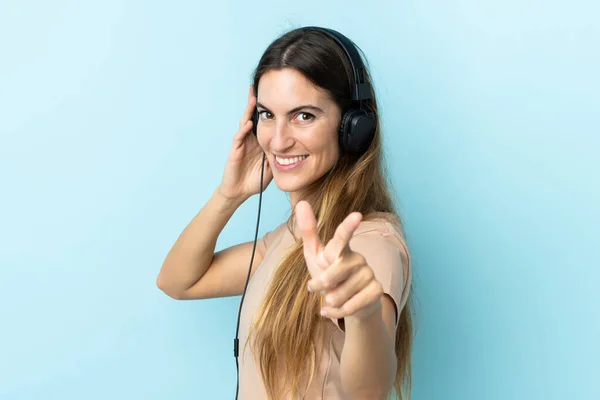 Joven Mujer Caucásica Aislada Sobre Fondo Rosa Escuchando Música Señalando —  Fotos de Stock