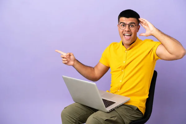 Jovem Sentado Uma Cadeira Com Laptop Surpreso Apontando Dedo Para — Fotografia de Stock