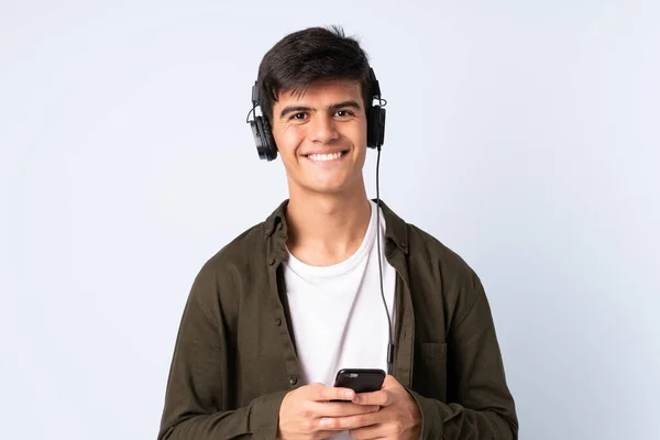 Knappe Man Geïsoleerde Blauwe Achtergrond Luisteren Muziek Met Een Mobiele — Stockfoto