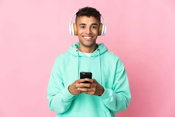 Fiatal Brazil Férfi Elszigetelt Rózsaszín Háttér Hallgat Zenét Egy Mobil — Stock Fotó
