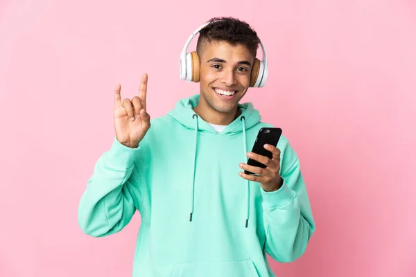 Jonge Braziliaanse Man Geïsoleerd Roze Achtergrond Luisteren Muziek Met Een — Stockfoto