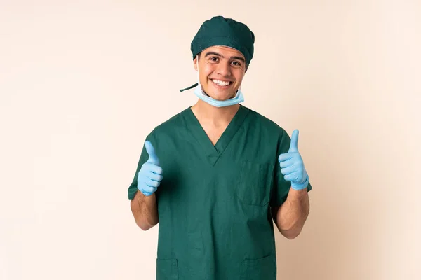 身穿蓝色制服的外科医生 背景孤立 他举起了一个大拇指 — 图库照片