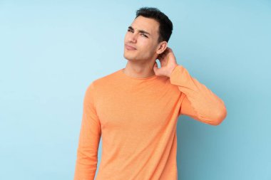 Kafkasyalı yakışıklı genç adam mavi arka planda izole edilmiş şüpheleri var.