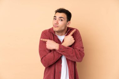 Beyaz tenli yakışıklı adam bej arka planda izole edilmiş. Yan taraftakilerin şüphesi var.