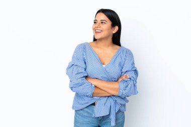 Beyaz arka planda yalnız, mutlu ve gülümseyen genç Latin bir kadın.